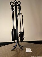 Cast iron fireplace tools set on stand with brush, shovel, and poker