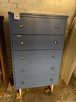 Blue retro-style six-drawer dresser with brass handles, visible dimensions label on top.