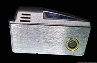 Side view of vintage 1960's Flamex pipe lighter showing chrome finish and green glass insert framed in gold tone ridged metal.