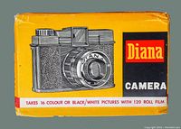 Original box of Diana camera with yellow and black design, stating it takes 16 colour or black/white pictures with 120 roll film.