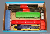 Top view of all included pieces in box: multiple HO scale train cars and track sections.