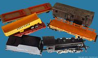 Vintage HO scale Santa Fe coal engine + flatbed cars, caboose, coal hopper, and track pieces on a blue surface.