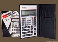 Photo of Sharp EL-506P scientific calculator alongside instruction manuals and a soft black protective case.