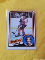 Front side of 1984 Daryl Sittler hockey card showing player image in Flyers uniform and inset portrait.