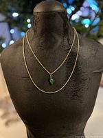 Front view of 14K gold chain necklace with green agate pendant on black mannequin bust