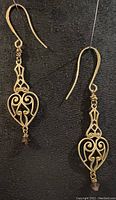 Full view of both antique brass earrings showing heart-shaped filigree design, wire wrapping, and crystal accents on gold-plated ear wires.
