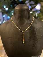 Single chain necklace with amber Swarovski crystal and gold-tone acorn pendant on mannequin bust