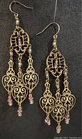 Full view of both brass chandelier earrings showing overall design, pink bead accents, and gold plated ear wires