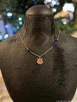 Black mannequin displaying copper-tone chain necklace with blue glass bead accents and copper fish pendant.