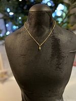 Full view of delicate gold plated necklace displayed on black mannequin bust, highlighting pendant and chain style.