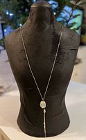 Front view of the necklace displayed on a black stand showing the glass bead pendant and the chain.