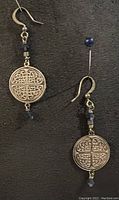 Pair of silver plated coin earrings with dark blue Swarovski crystals laid on black fabric.