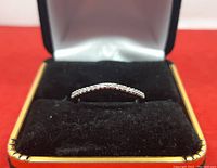 Front view of 10k white gold diamond band displayed in black velvet box
