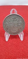 Front side of the 1953 Canadian 50 cent silver coin showing the Canadian coat of arms and inscriptions.