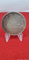 Obverse side of the 1965 Canada silver dollar coin showing the canoe design with two paddlers and the date below.
