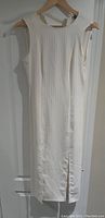 White sleeveless Topshop dress hanging on a wooden hanger showing full length and fabric detail