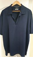 Front view of navy blue Ben Hogan Performance golf shirt on hanger