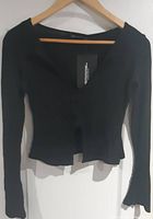 Black women's knit long-sleeve top on hanger highlighting square neckline and scalloped hem