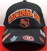 Front view of the black American Needle hat with NHL Original Six and NHL team logos embroidered in orange, black, white, red and blue.