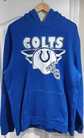Front view of blue Indianapolis Colts hoodie with vintage style large white print including text and helmet graphic.