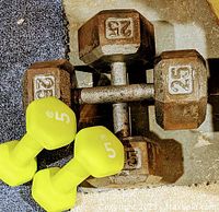 Photo of two rusty 25-pound hex dumbbells and two yellow plastic-coated 5-pound dumbbells.