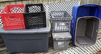 Photo showing three open lattice milk crates in red, black, and grey along with multiple plastic storage tubs including a large grey with fitted lid and blue tub with foldable lid.