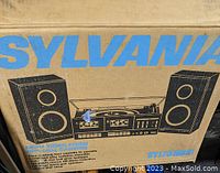 Original packaging box of the Sylvania stereo system showing graphic illustration of the unit with two speakers, record player, cassette player, and radio.