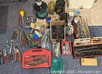 Full overview of boxed tools and supplies including drill bits, nails, screws, hand tools, electrical wire, and other hardware items.