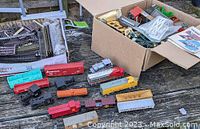Six model train engines in various colors and designs with some additional freight cars and train track sections