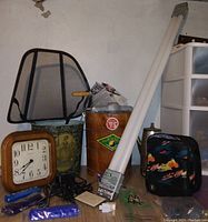 Photo showing the wooden wall clock, green metal waste basket with vintage floral design, White Mountain wooden ice cream bucket, black lunch bag with colorful abstract design, two LED fluorescent tube lights, and various small items including cords and blue flashlight.
