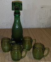 Green glass dog-shaped decanter surrounded by four matching green glass mugs.