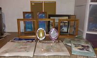 Photo of assorted empty picture frames in various sizes and finishes including wood and metallic oval frames, arranged on a table.