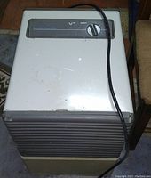 Front view of vintage beige and gray Air-O-Swiss ultrasonic humidifier with control knob and power cord.