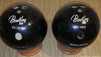 Front view of black spherical Bowling 300 branded ice bucket and decanter holder resembling bowling balls with finger holes and white print.