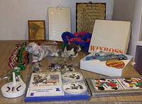 Overall group shot showing plush toys, beads, Winross game box, coasters, and holiday puzzles arranged on table