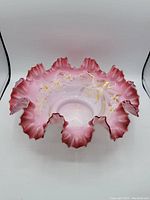 Top and side views of an antique handpainted glass bridal bowl with ruffled pink edges and floral gold accents.