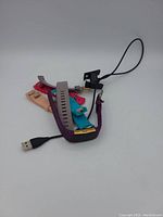 Image showing Fitbit device with cracked screen, USB charger, and multiple colorful bands.