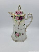 Handpainted Nippon chocolate pot with pink and purple flowers and gold accents, visible hairline crack on lid, white ceramic base