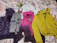 Full lot of 7 Lululemon scuba hoodies in size 8, showing various colors and patterns including purple, grey, white floral, pink ombre and yellow.