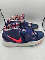Side view of navy blue Nike basketball shoe showing red swoosh and patterned inner lining.