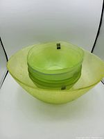 Front view of the set showing large bowl with smaller bowls stacked inside, showing the translucent green color and textured pattern.