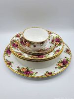 Photo showing stacked tea cup, saucer, bread plate and dinner plate with Royal Albert Old Country Rose floral pattern and gold trim