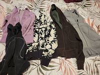 Lot of five Lululemon size 4 scuba hoodies laid out on a bed showing all items together in multiple colors and patterns.