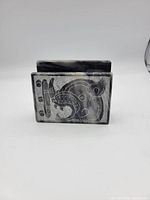 Front angle showing engraved indigenous animal face on rectangular stone napkin holder