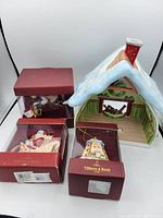 Full lot showing snow-covered cottage decoration with chimney and three boxed Villeroy & Boch Christmas hanging ornaments in original red packaging