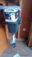 Front view of Johnson 4.0 outboard motor mounted inside wooden structure, showing overall condition and lower propeller.