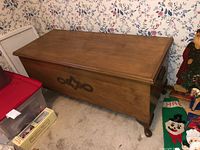 Front view of cedar chest on carpet showing overall shape and carved front panel