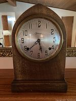 Front view of Sessions 8 day clock with numbers and clock hands visible, wooden arched case