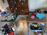 Two folding card tables with various items on them, one green and one brown, showing overall condition and size.
