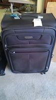 Front view of large black Samsonite suitcase showing two zippered front pockets and handle.
